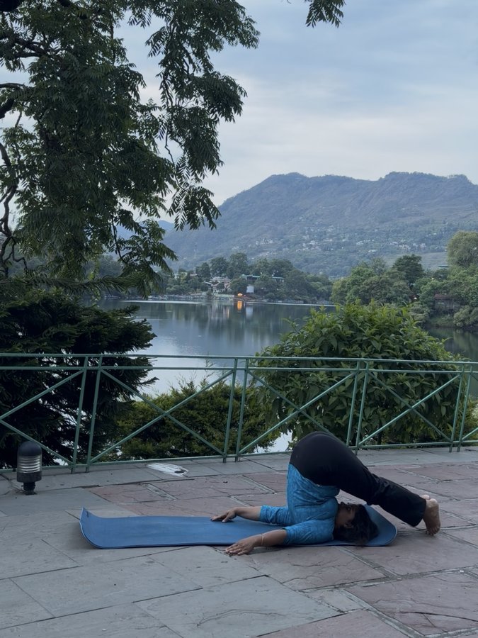 Minal practising halasana by the lake